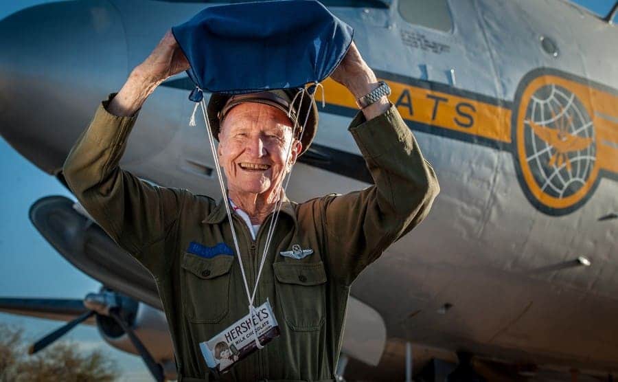 Lt. Gail Halvorson holding a make-shift parachute with chocolates attached next to an aircraft
