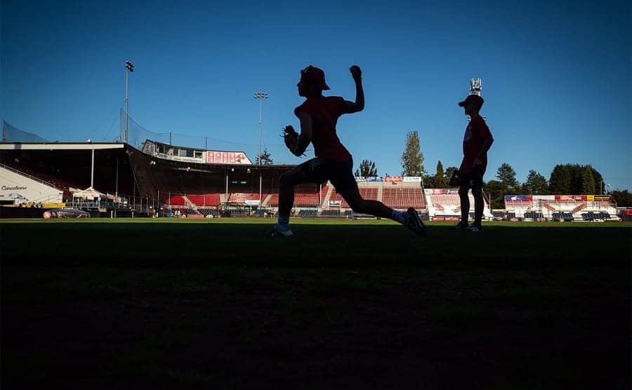 A youth baseball field with silhouettes of two young players warming up
