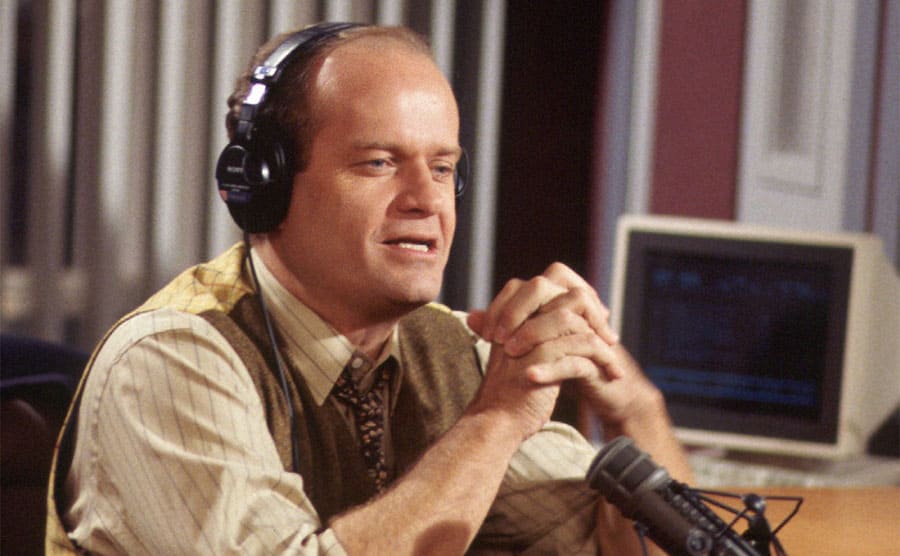 Kelsey Grammer wearing headphones doing a radio show on the show Frasier