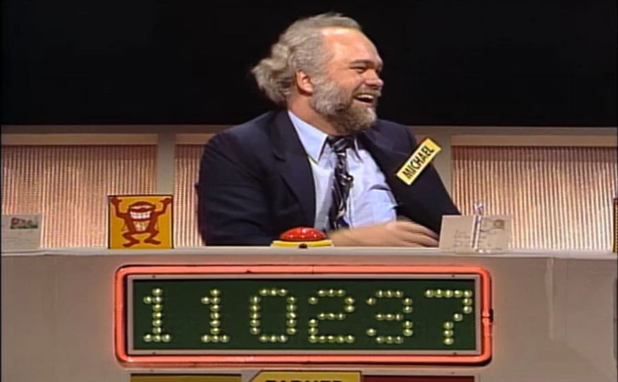 Michael Larson behind a desk with his guess on it