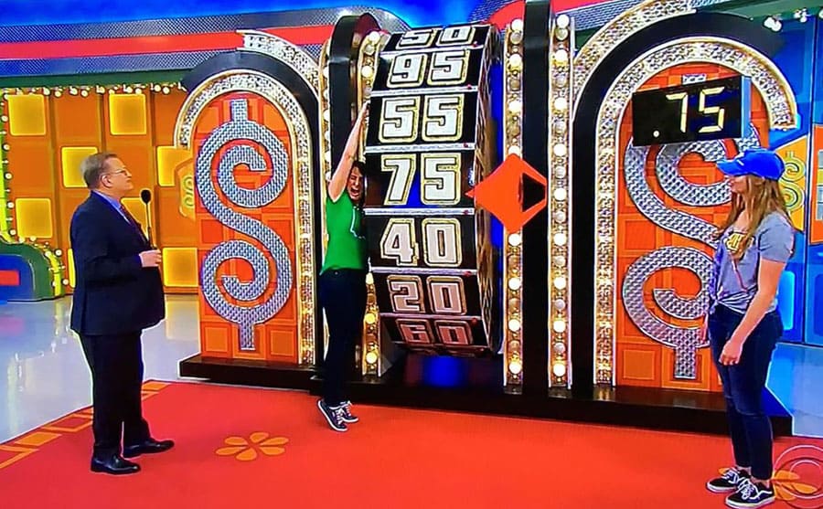 A woman spinning the wheel while another woman stands under 75 cents and Drew Carey standing on the side