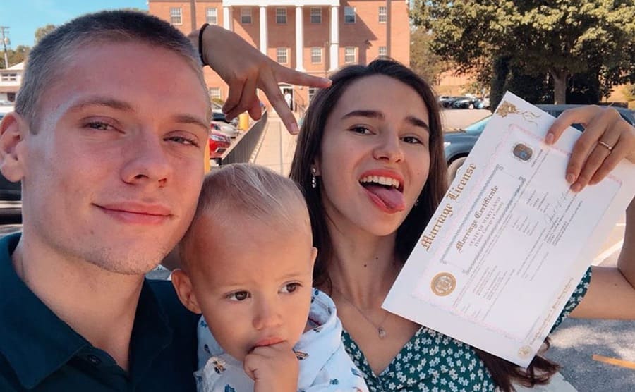 Olga and Steven holding their marriage license posing for a selfie with their son