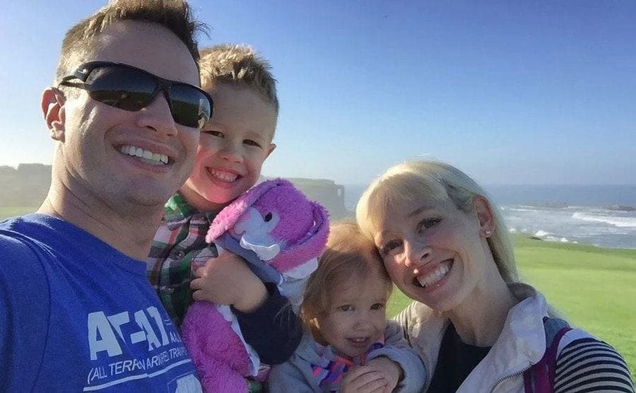 Sherri and Keith Papini hugging with their two little children and smiling