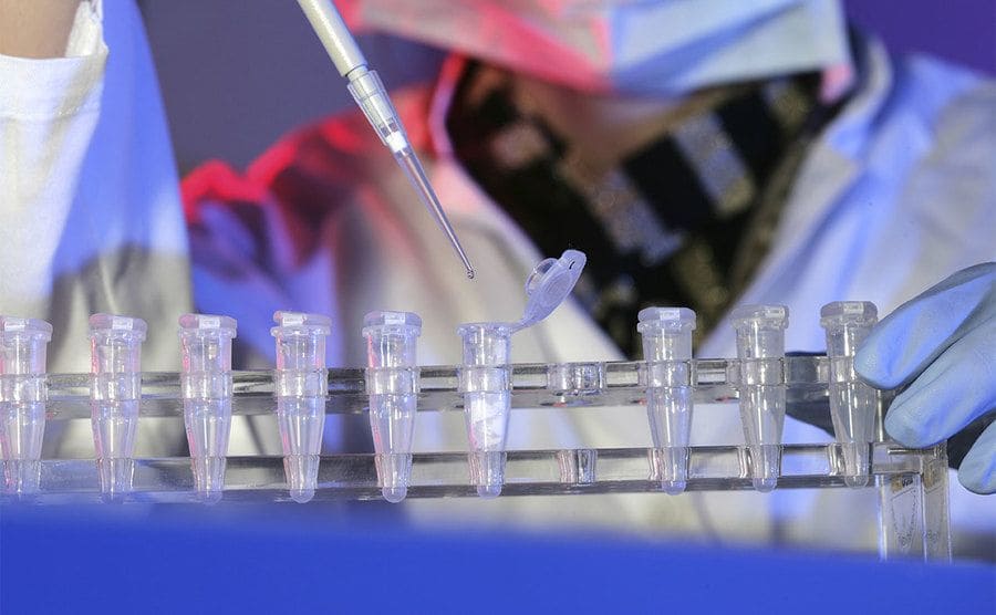 A laboratory worker putting a syringe into a test tube at a DNA analysis laboratory