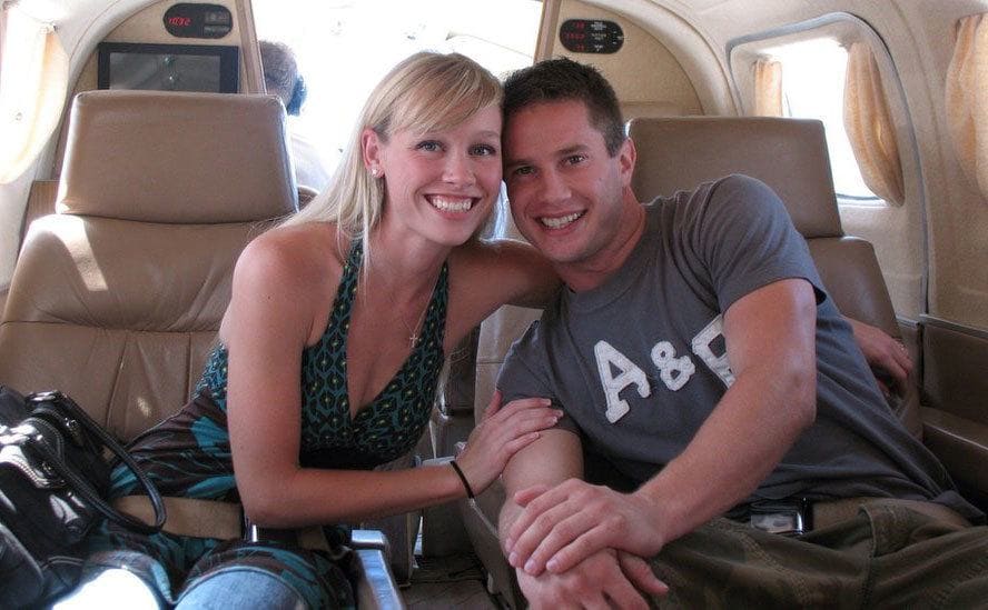 Keith and Sherri sitting in an airplane hugging and smiling