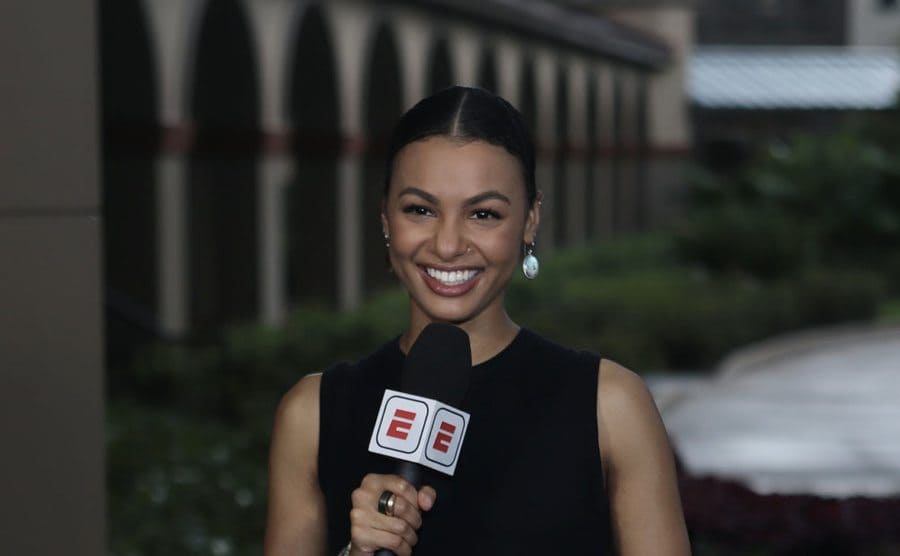 Malika Andrews holding a microphone
