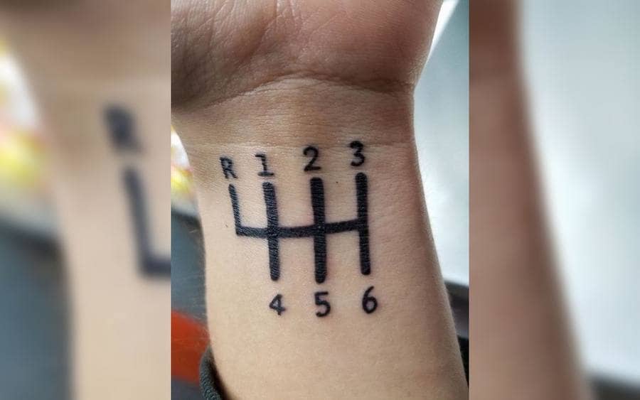 A tattoo of a gear of a car on a guy's arm
