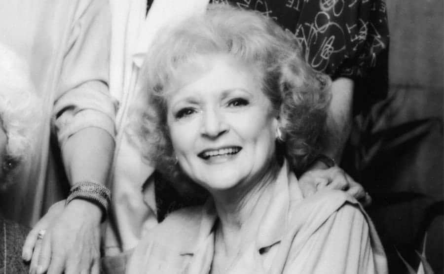 The cast of the Golden Girls posing for a portrait with two women sitting on a bench and two women standing in the back