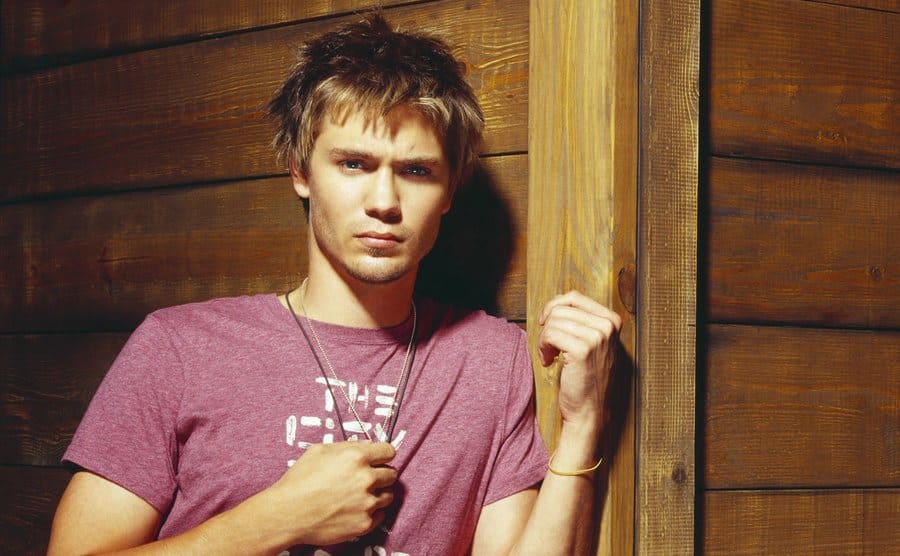 Chad Michael Murray posing leaning on a wooden cabin
