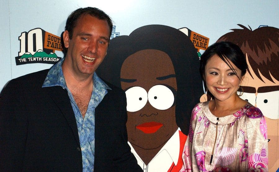 Trey Parker with his wife Ema in front of a poster for South Park