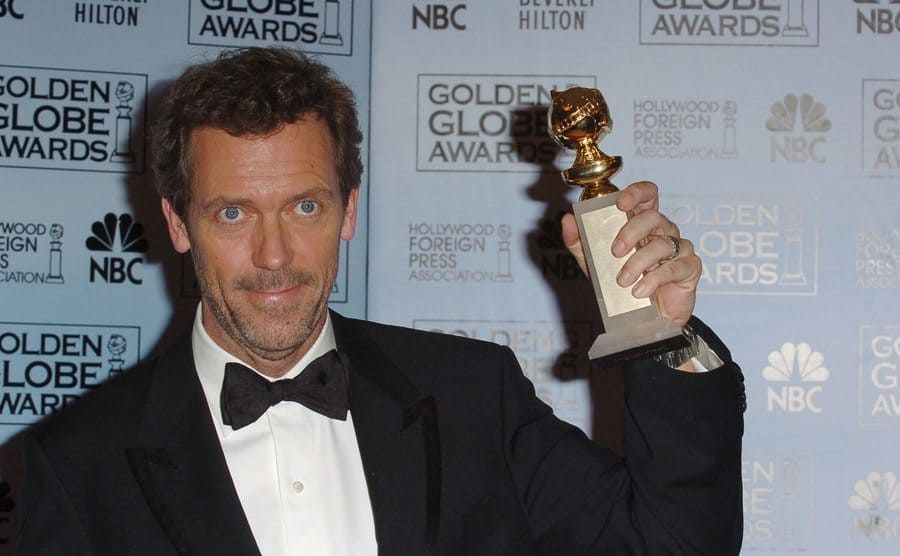 Hugh Laurie holding a Golden Globe Awards for his role in House