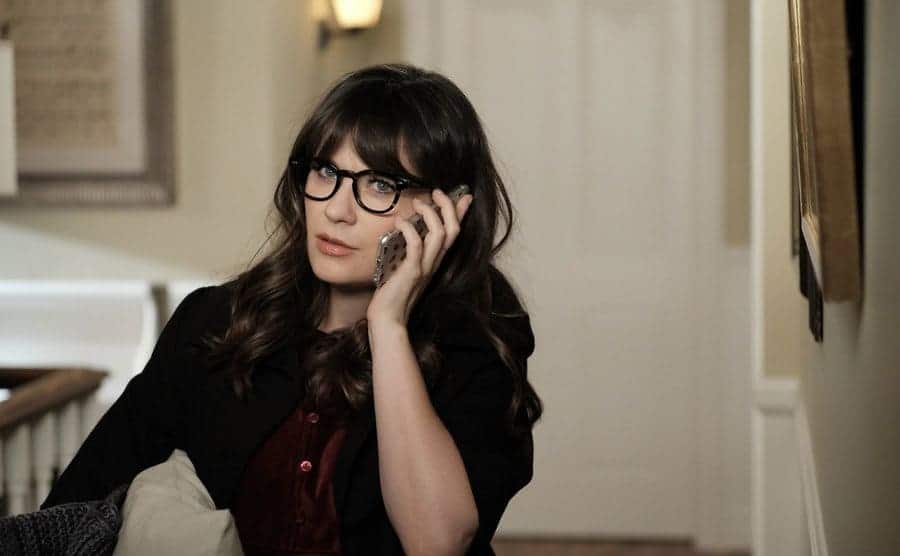 Zooey Deschanel on the phone in the hallway of a house in a scene from New Girl