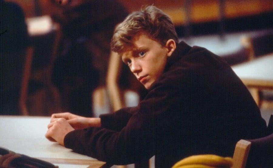 Anthony Michael Hall as Brian Johnson sitting at a library table in a scene from The Breakfast Club