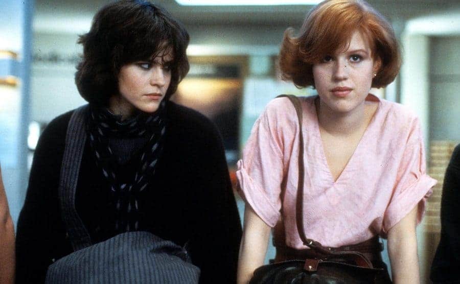 Ally Sheedy and Molly Ringwald sitting on a library desk in The Breakfast Club