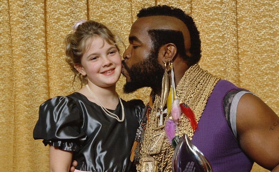Mr. T giving Drew Barrymore a kiss on the cheek while holding his Peoples’ Choice Award in 1984