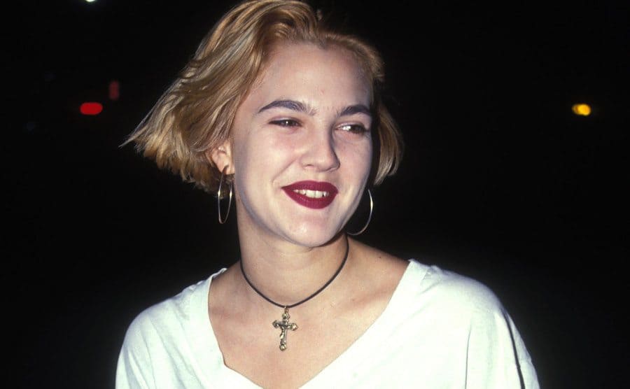 Drew Barrymore on a dark street wearing a white t-shirt in 1992
