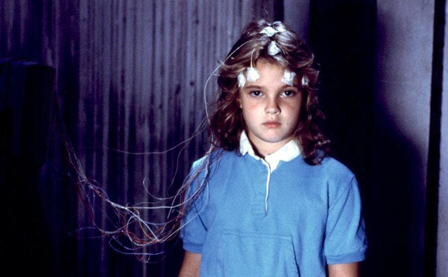 Drew Barrymore as Charlie starring forward with wires attached to her head in the film Firestarter