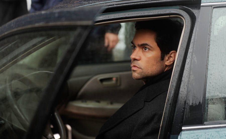 Danny Pino as Nick Amaro sitting in the driver's seat of a green car