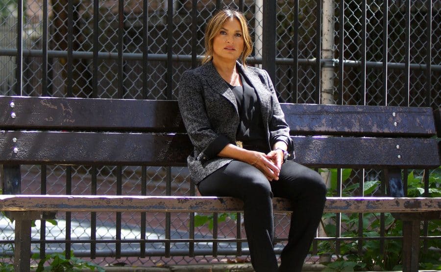 Mariska Hargitay as Olivia Benson sitting on a park bench on the set of Law and Order