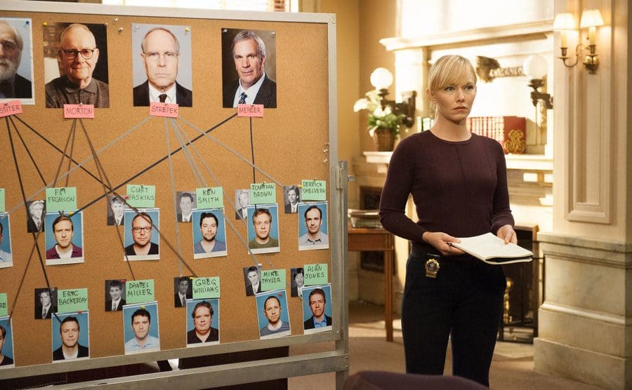 Kelli Giddish as Amanda Rollins standing in front of a board with suspects photographs pinned up