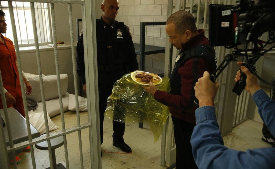 Ice T and Alex Hernandez in a behind the scenes shot of him bringing food to a jail cell