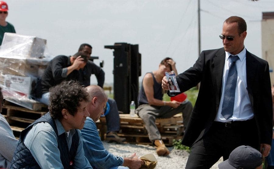 Christopher Meloni as Elliot Stabler showing a photograph to citizens asking if they have seen this woman in a scene from Law and Order