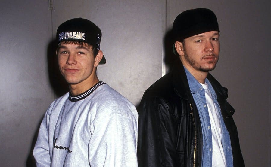 Mark and Donnie Wahlberg posing back to back arriving at an event