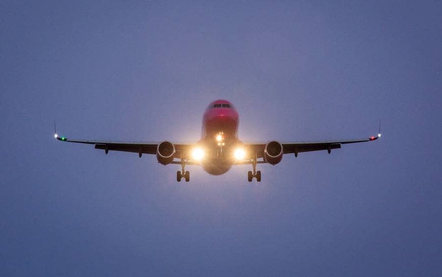 View of an airplane from the front with lights on and blue background
