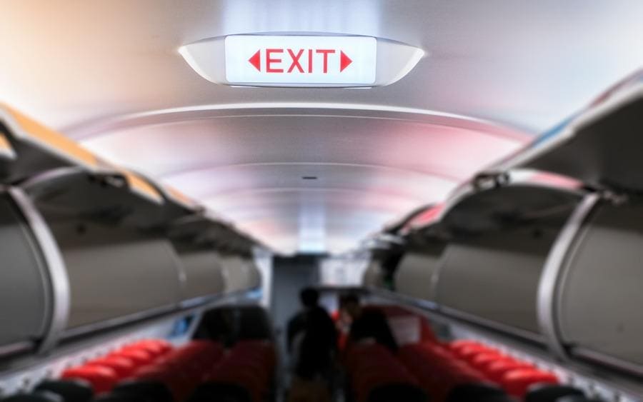 Emergency exit sign on the ceiling inside the passenger aircraft cabin