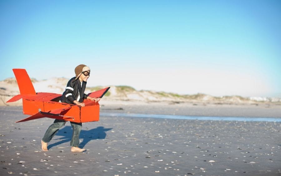 Boy running with a toy airplane on the beach