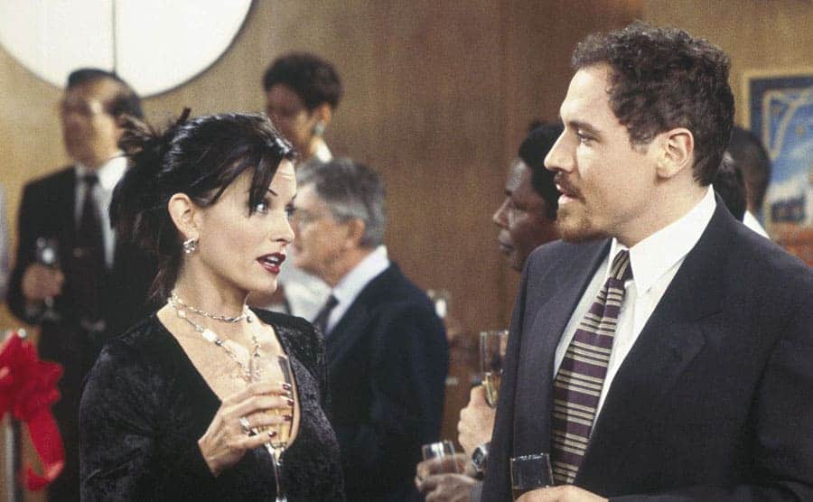 Courteney Cox and Jon Favreau mingling at an event in a scene from friends 