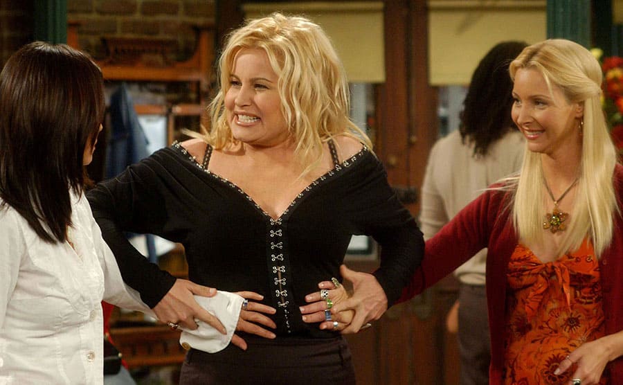 Jennifer Coolidge holding Courteney and Lisa’s hands on her stomach while smiling 