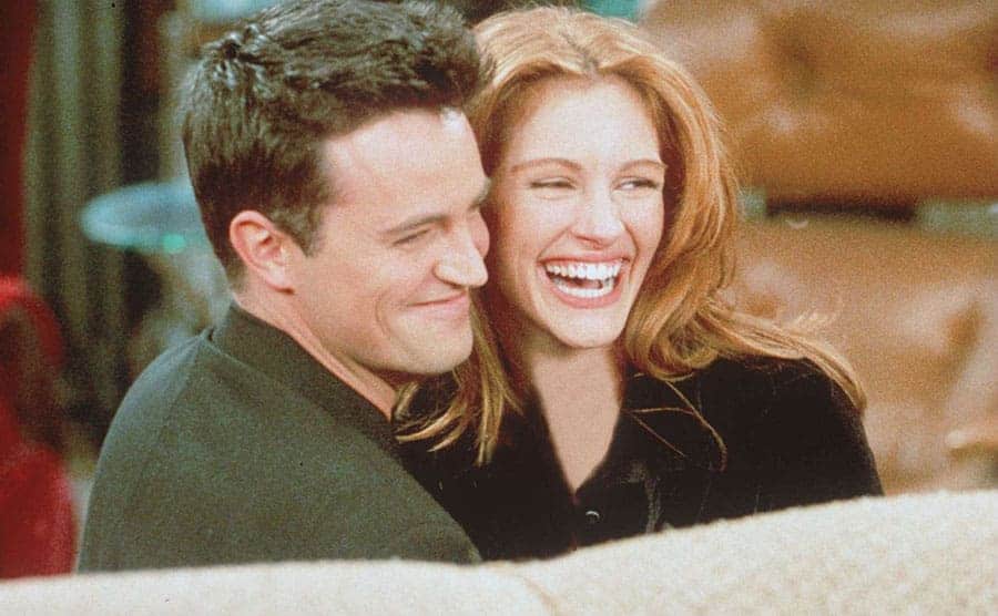 Matthew Perry and Julia Roberts smiling and laughing in a scene from Friends 