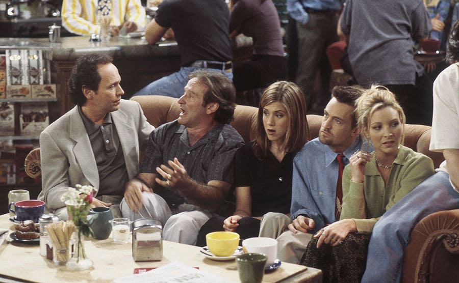 Billy Crystal and Robin Williams talking together with the rest of the cast sitting around them 