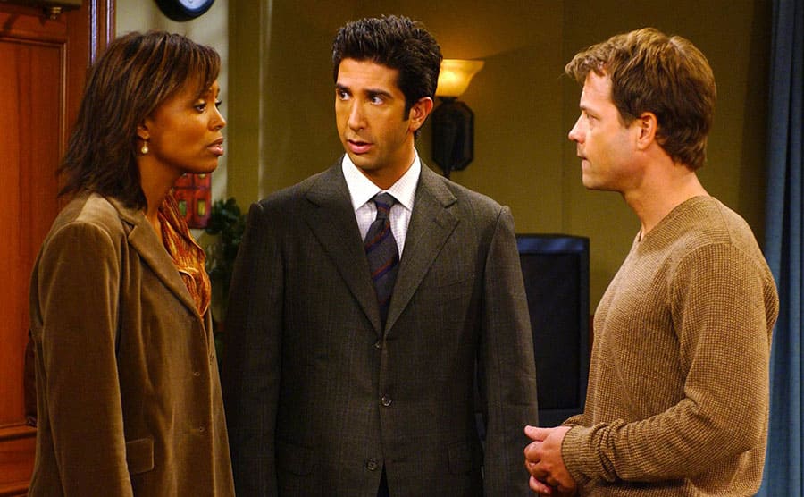 Aisha Tyler, Greg Kinnear, and David Schwimmer standing around a doorway together 
