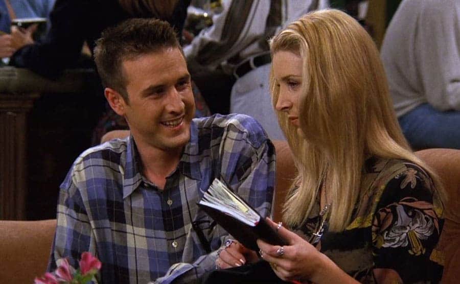 David Arquette talking to Lisa Kudrow on the café couch in a scene from Friends 