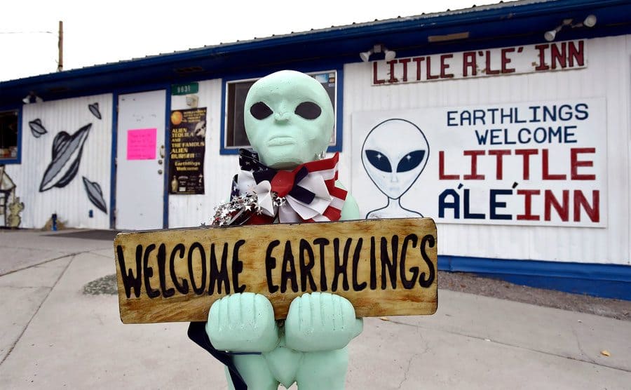 An alien-like statue displays a sign welcoming guests to the Little A'le' Inn restaurant and gift shop