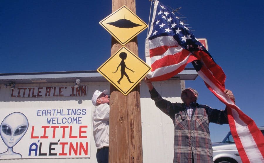 During the official opening of Extraterrestrial highway, Joe Travis, owner of Little A'le' Inn putting up an American flag next to space alien sign.