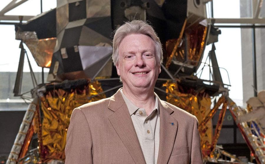 Roger Launius is standing before a spacecraft.