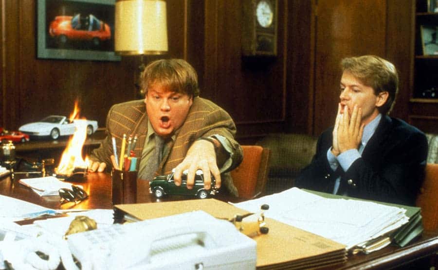 Chris Farley playing with a toy truck with David Spade looks shocked and uncomfortable in a scene from Tommy Boy