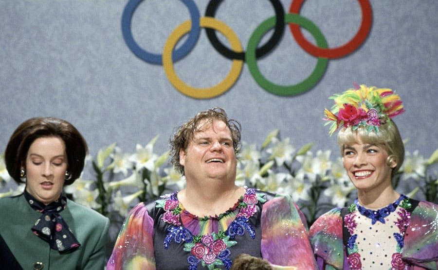 Chris Farley with Melanie Hutsell and Nancy Kerrigan sitting in the area you receive a figure skating score in an SNL sketch