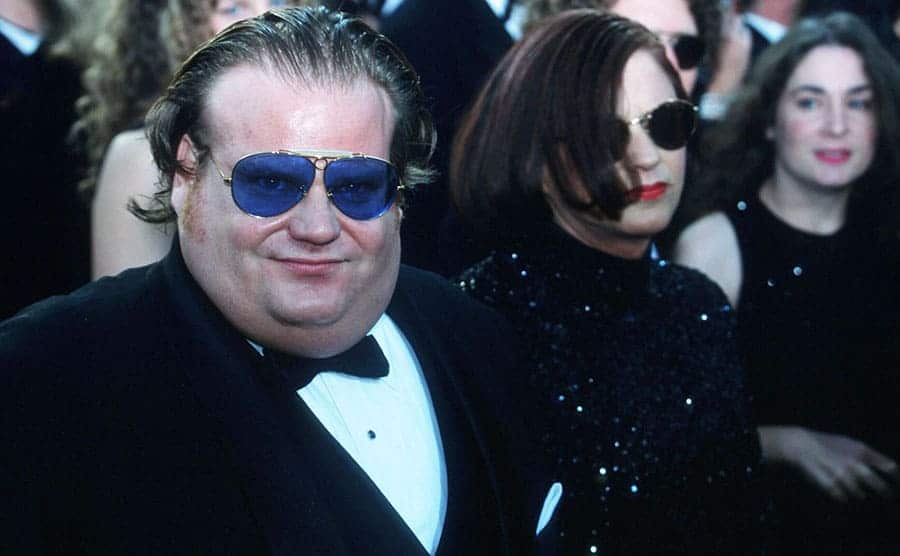 Chris Farley on the red carpet with a woman behind him