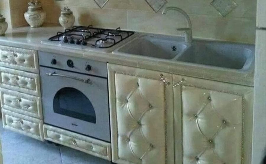 A kitchen in which all the drawers and cupboards are covered in cream-colored tufted design. 