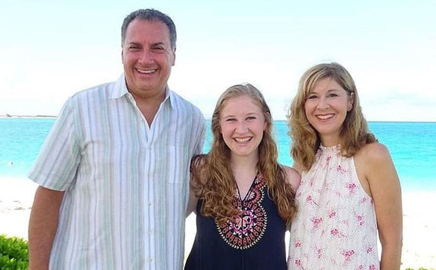 Rebecca Cartellone posing with her arms around her parents Joseph and Jennifer Cartellone on the beach.