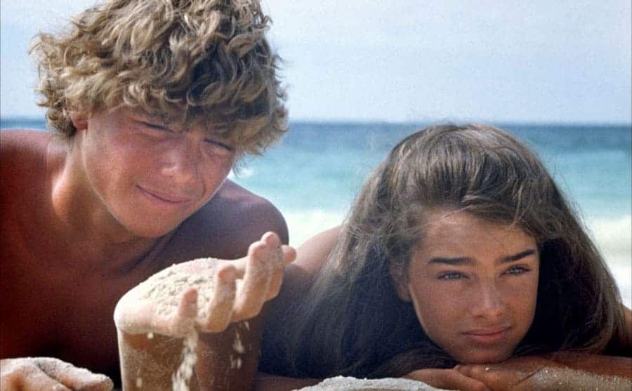 Christopher Atkins and Brooke Shields hanging out on the beach together in a scene from The Blue Lagoon