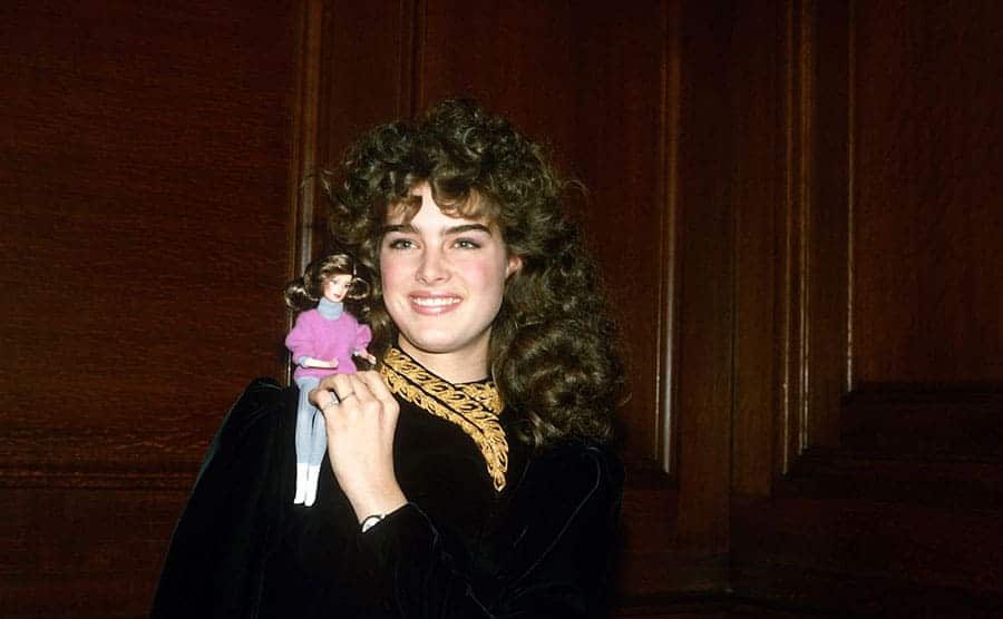 Brooke Shields holding the tiny doll on her shoulder that resembles her