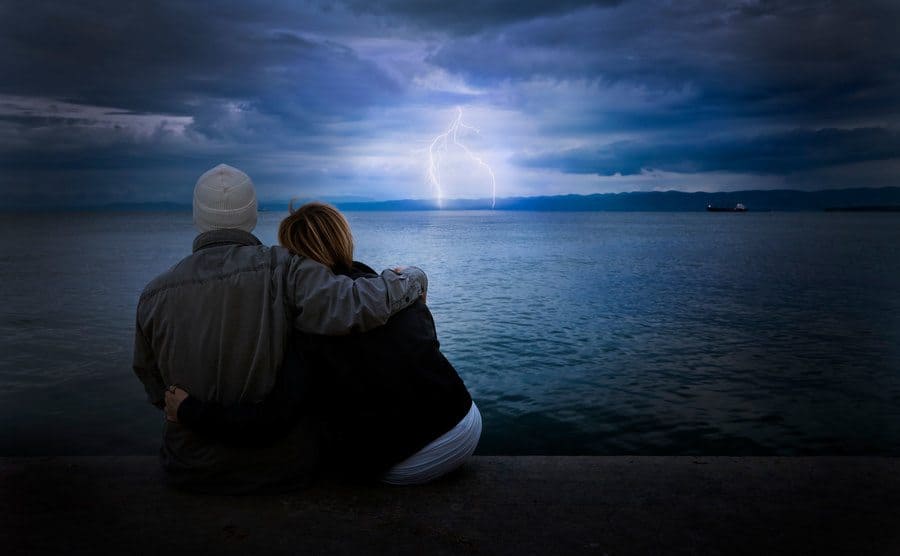 Couple looking at thunderstorms on the beach.