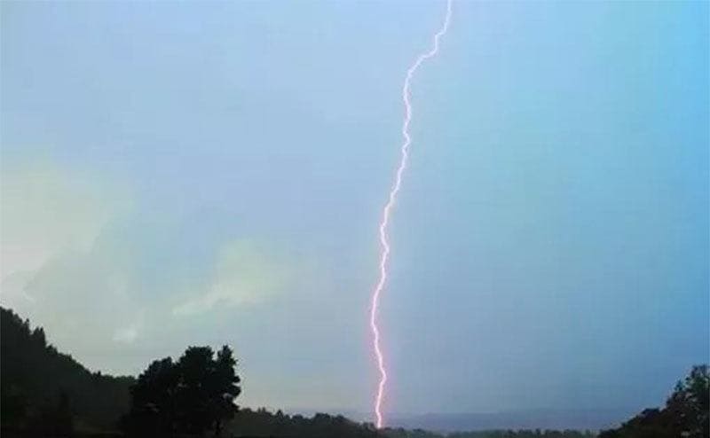 A lightning rod striking the ground on a clear sky day. 