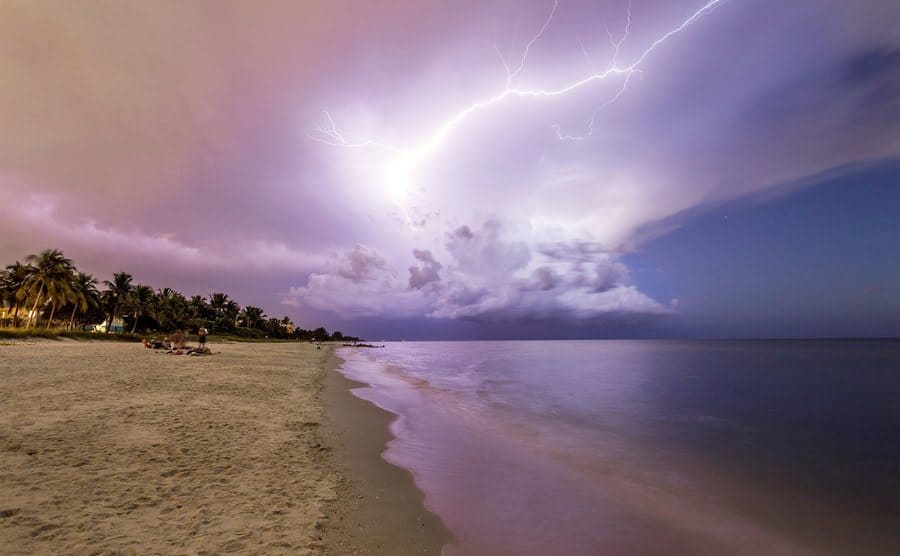 Naples beach and calm ocean during a lightning storm at sunset, Florida, USA.
