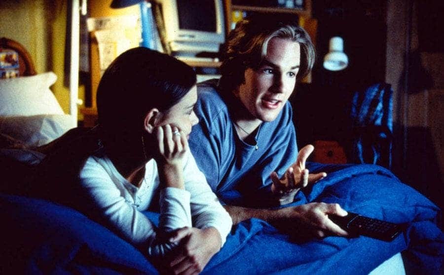 Joey and Dawson watching a movie from the edge of the bed
